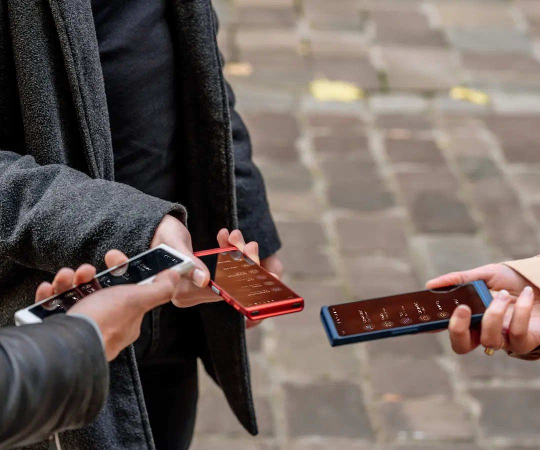 Tres amigos sosteniendo alegremente sus traductores, conversando y compartiendo momentos juntos. 